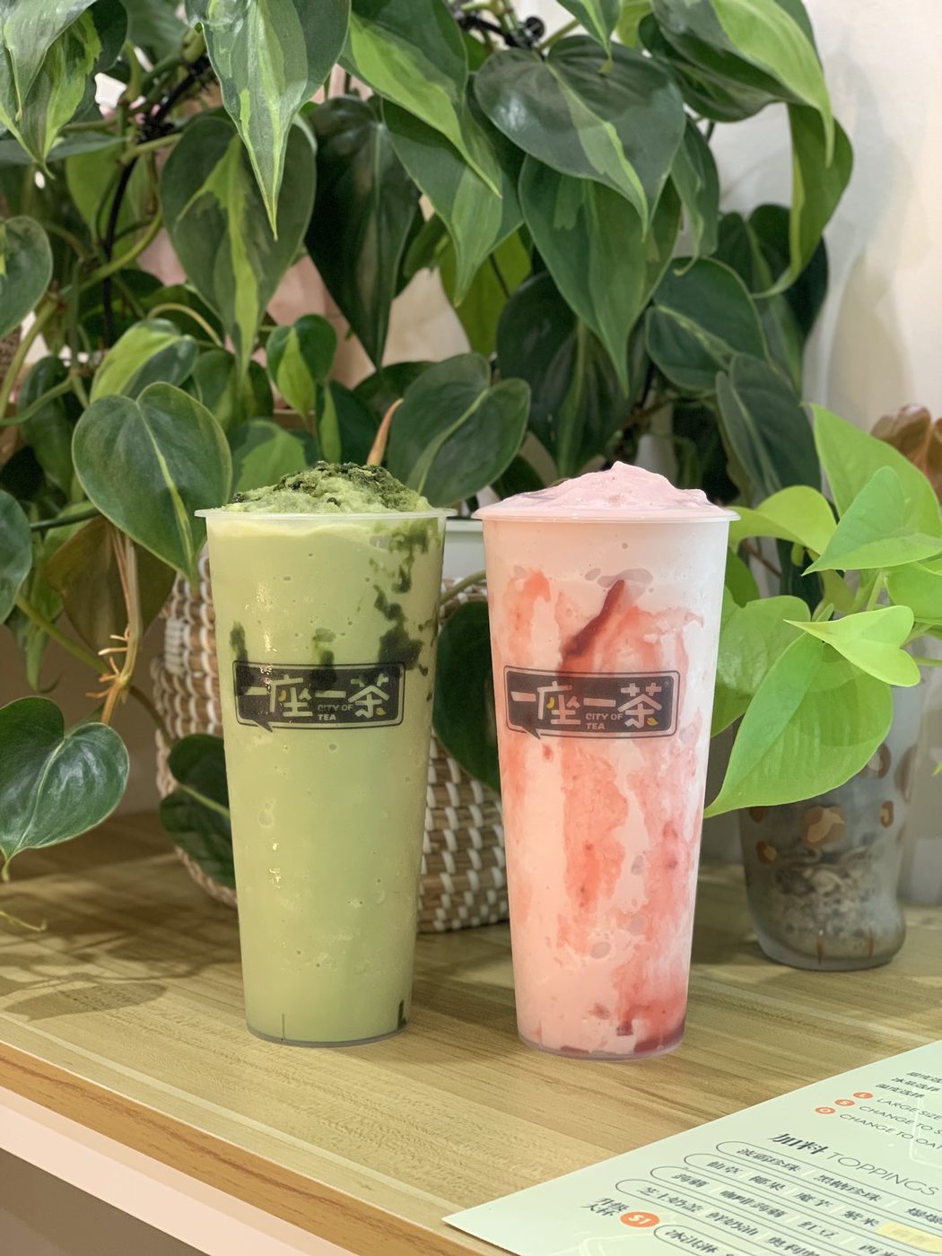 Green and pink tea drinks among leafy plants